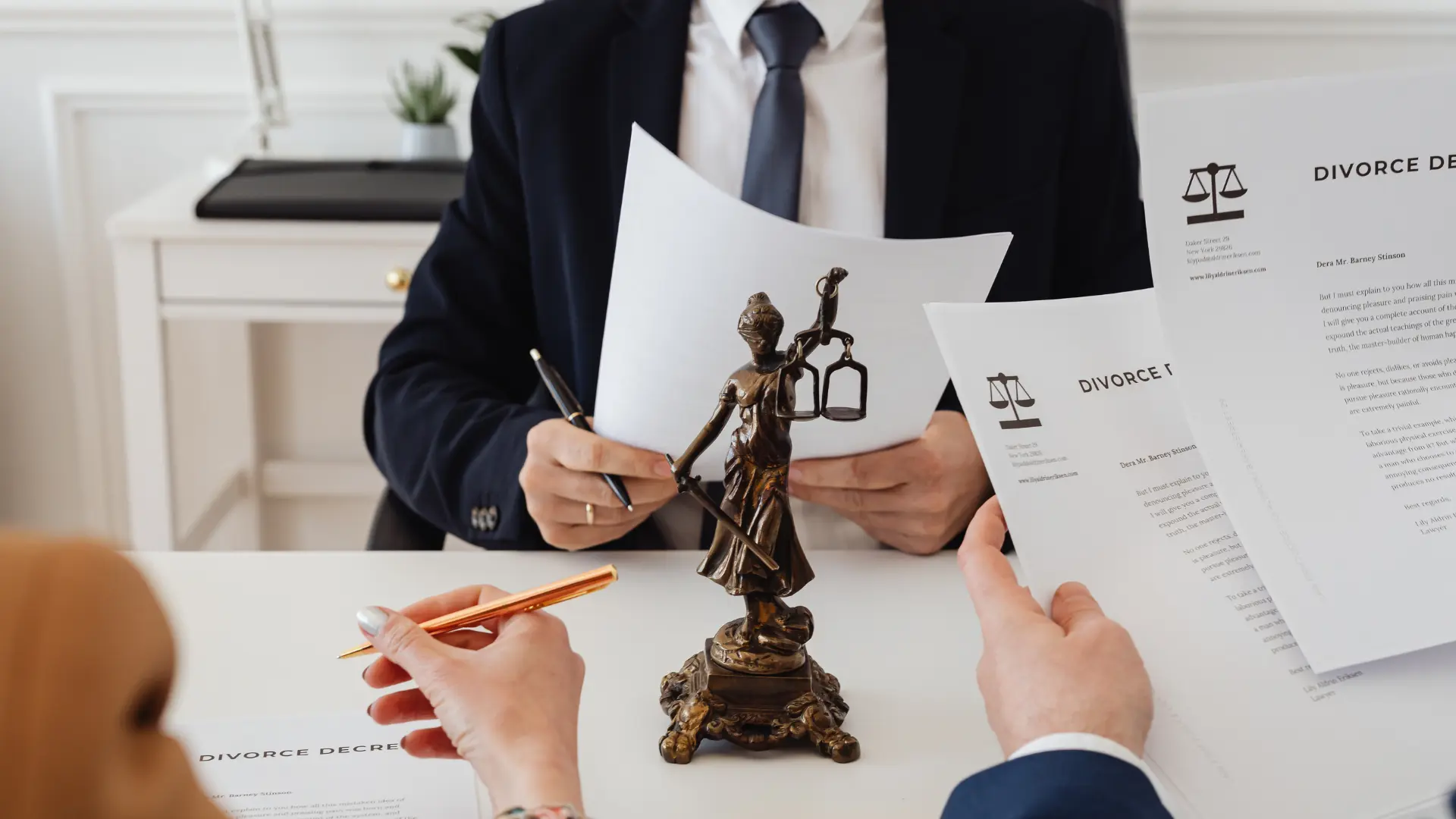Lawyers reviewing legal documents with a Lady Justice statue on the table.