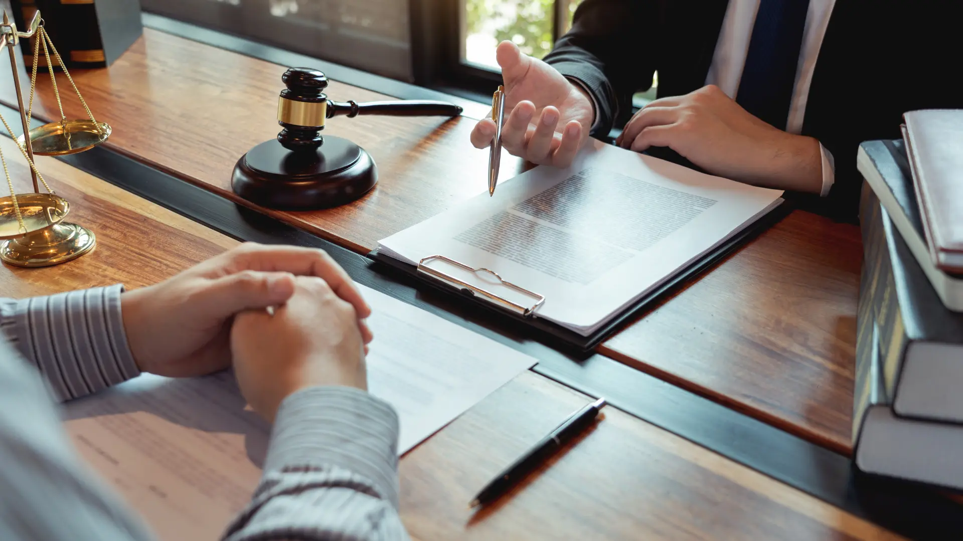 Lawyer pointing to legal documents during a meeting with a client and a gavel on the table