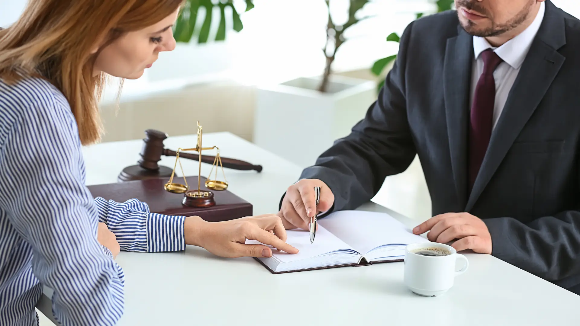 Lawyer and client discussing documents at a desk with a gavel and legal scales