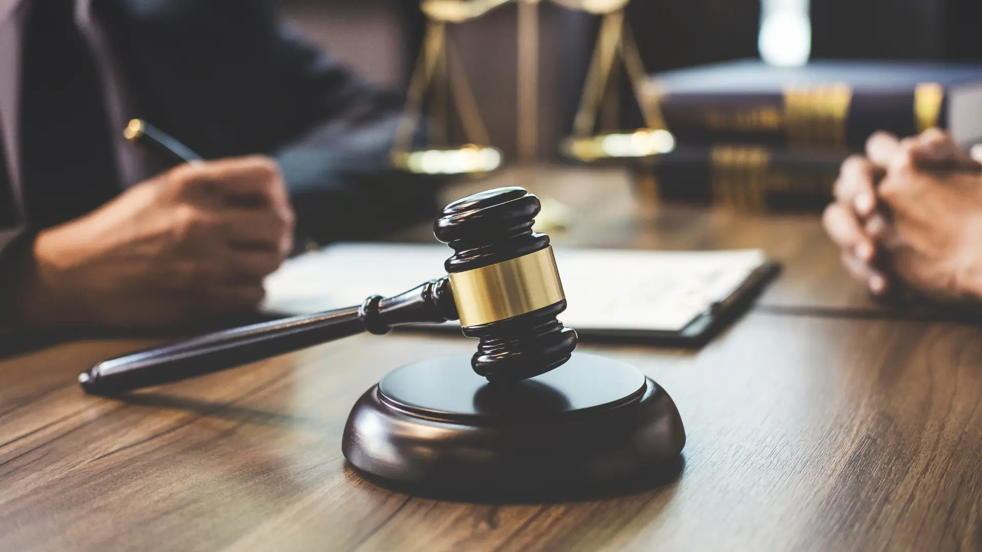 Close-up of a gavel on a desk with legal scales in the background.