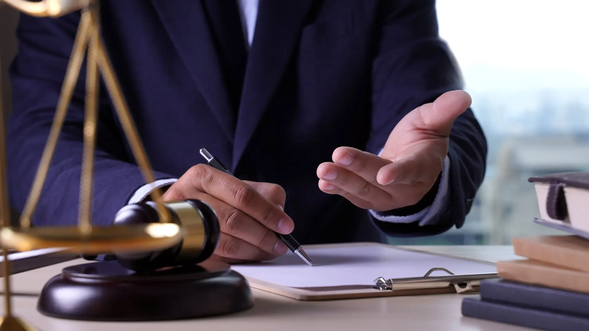 Lawyer gesturing while noting on clipboard beside gavel