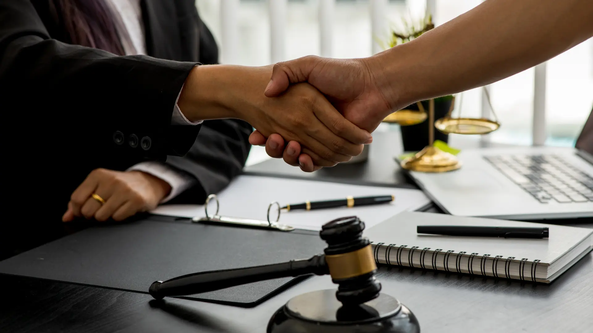 Handshake over desk with gavel in foreground